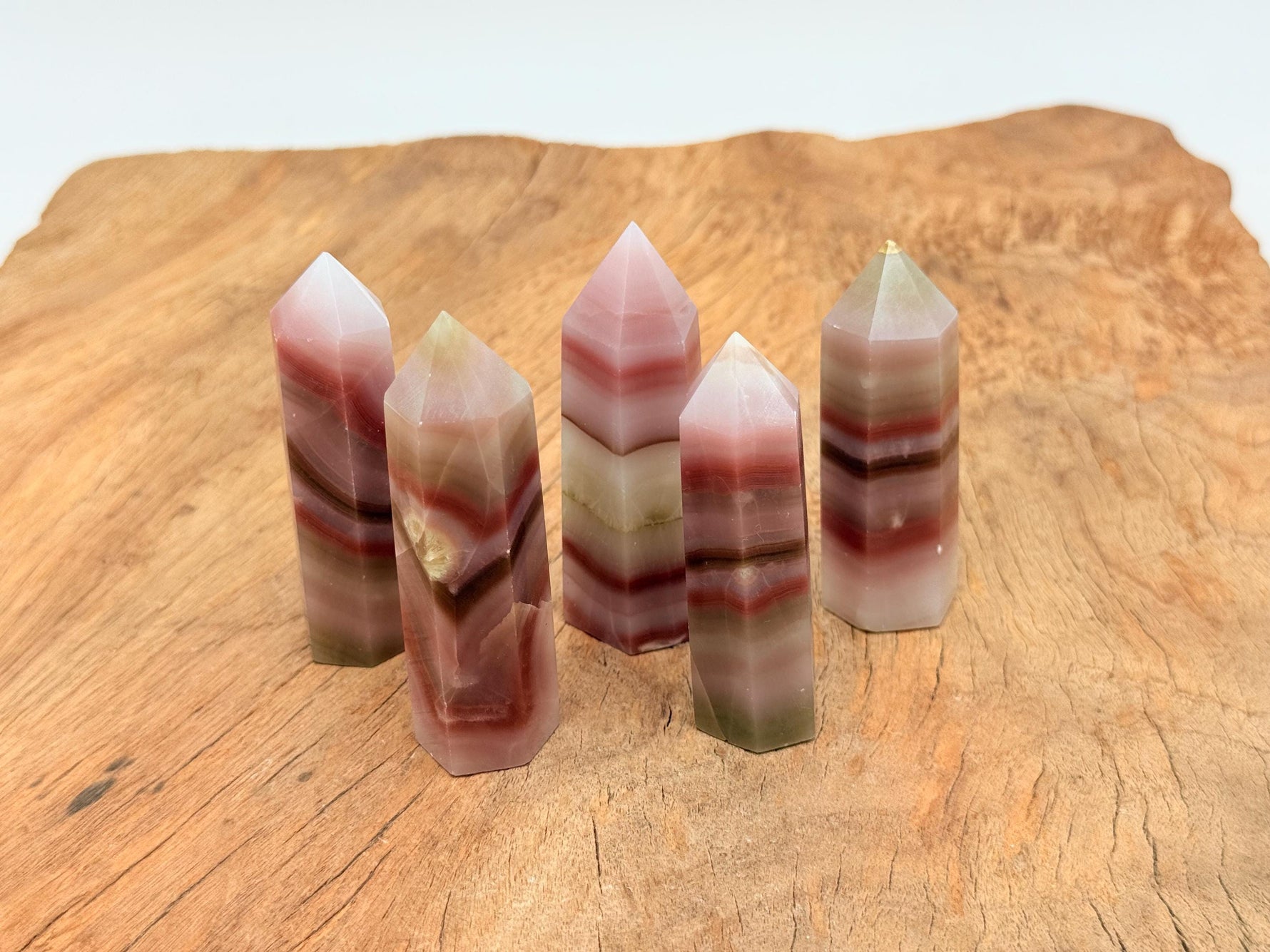 Pink banded calcite obelisk tower crystal from GemstoneGO, showcasing layered pink and white bands with a pointed top.