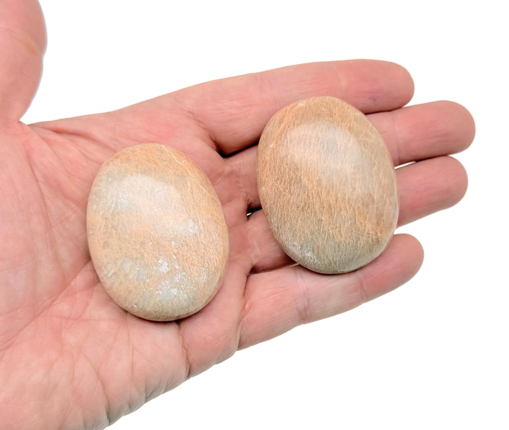 Peach Moonstone palm gemstone spa stone from GemstoneGO, smooth oval-shaped healing crystal for relaxation or meditation.