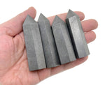 Shungite obelisk tower crystal from GemstoneGO, featuring a polished black stone with natural striations and a pointed obelisk shape.