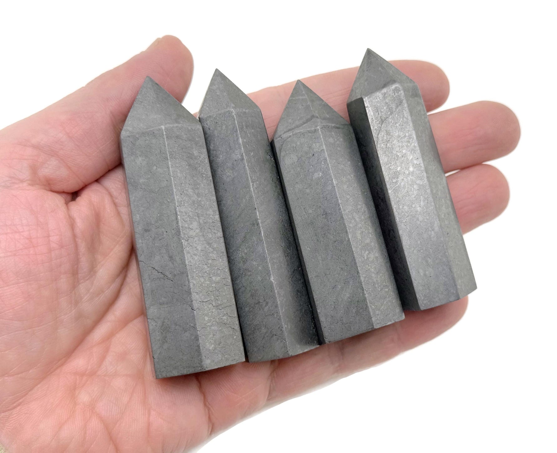 Shungite obelisk tower crystal from GemstoneGO, featuring a polished black stone with natural striations and a pointed obelisk shape.