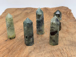 Prehnite obelisk tower crystal from GemstoneGO, showcasing a smooth green gemstone with natural mineral patterns.
