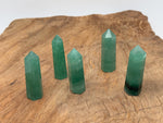 Green strawberry quartz obelisk crystal tower with polished facets, showcasing vibrant green color and natural gemstone details.
