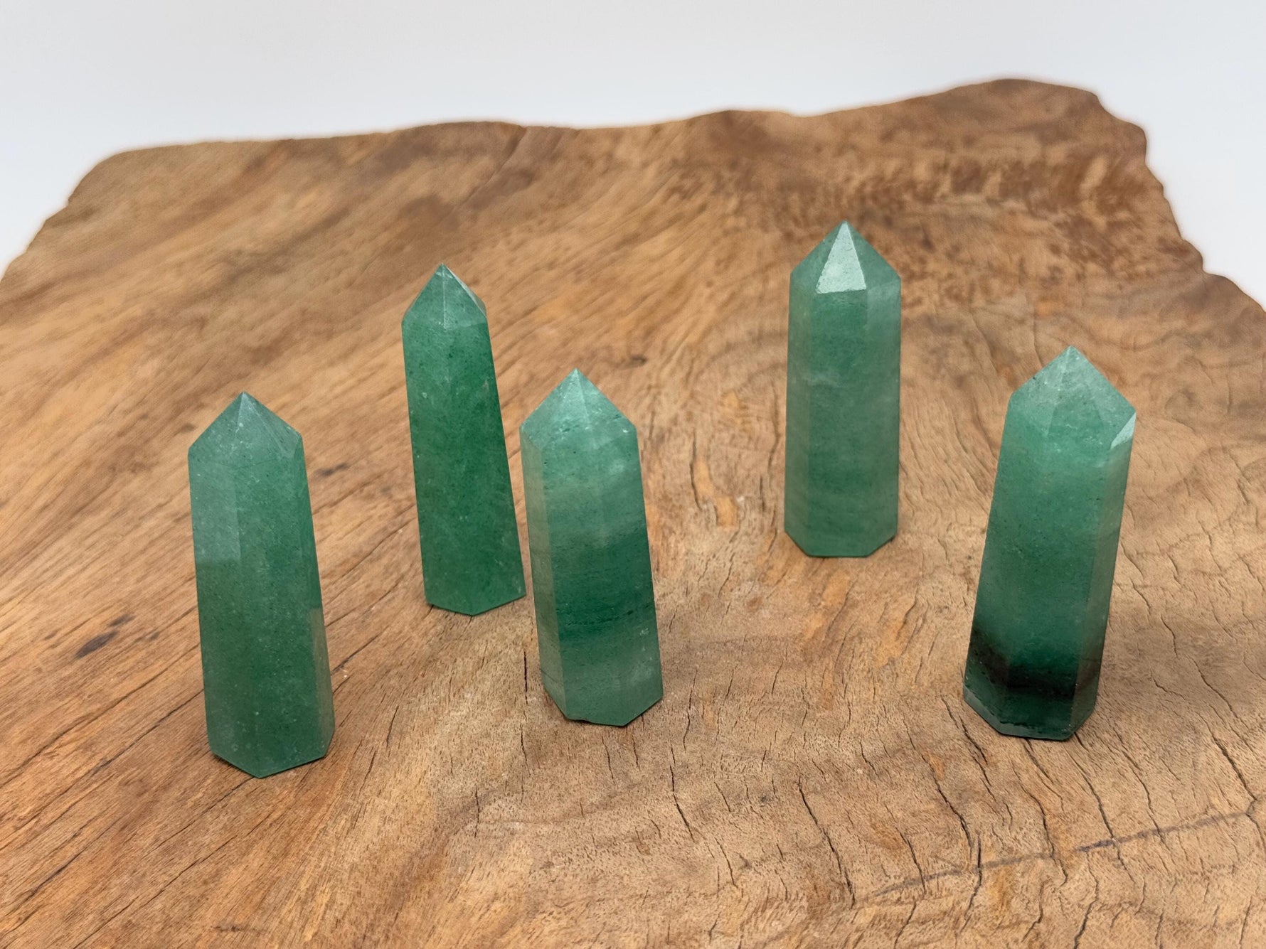 Green strawberry quartz obelisk crystal tower with polished facets, showcasing vibrant green color and natural gemstone details.