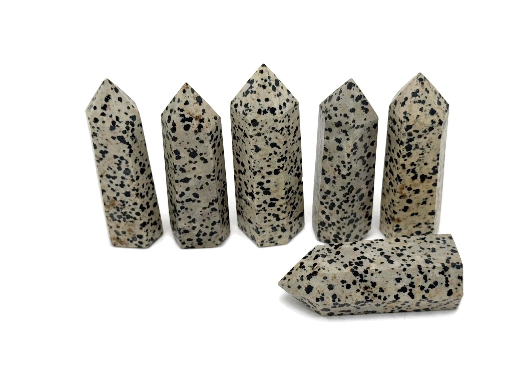 Dalmatian Jasper obelisk tower crystal from GemstoneGO, featuring black spots on beige stone with a pointed top.