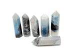 Trolleite obelisk tower crystal from GemstoneGO, featuring a tall, polished blue mineral with natural striations and a pointed top.
