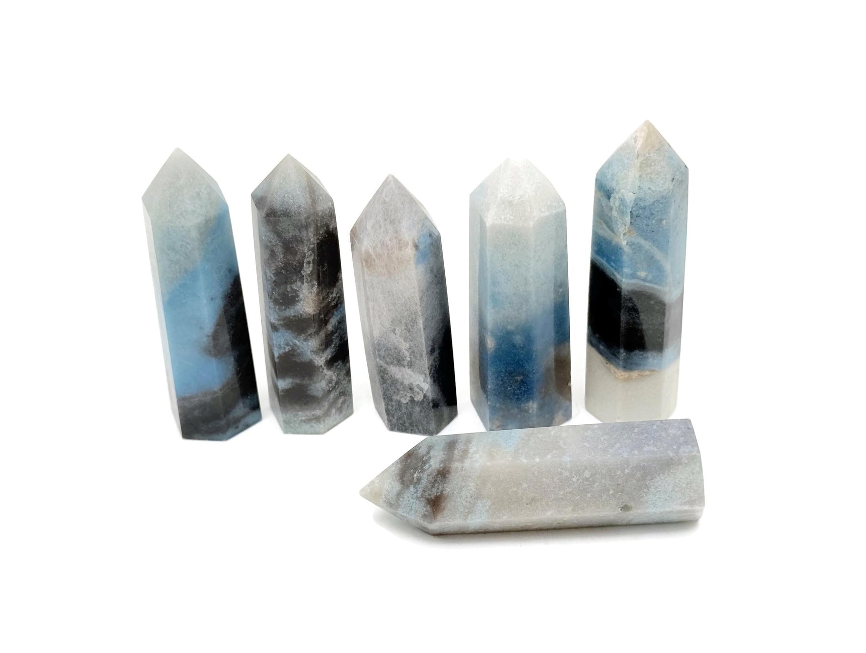 Trolleite obelisk tower crystal from GemstoneGO, featuring a tall, polished blue mineral with natural striations and a pointed top.