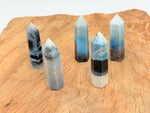 Trolleite obelisk tower crystal from GemstoneGO, showcasing blue-green mineral with natural crystal formation and pointed shape.