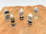 Fluorescent fluorite agate obelisk tower crystal with vibrant green and purple hues, gemstone display by GemstoneGO.