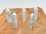 Mexican White Agate obelisk tower crystal from GemstoneGO, showcasing smooth, polished white stone with natural banding and unique patterns.