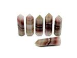Pink banded calcite obelisk tower crystal from GemstoneGO, showcasing vibrant pink and white banded patterns on a smooth polished surface.