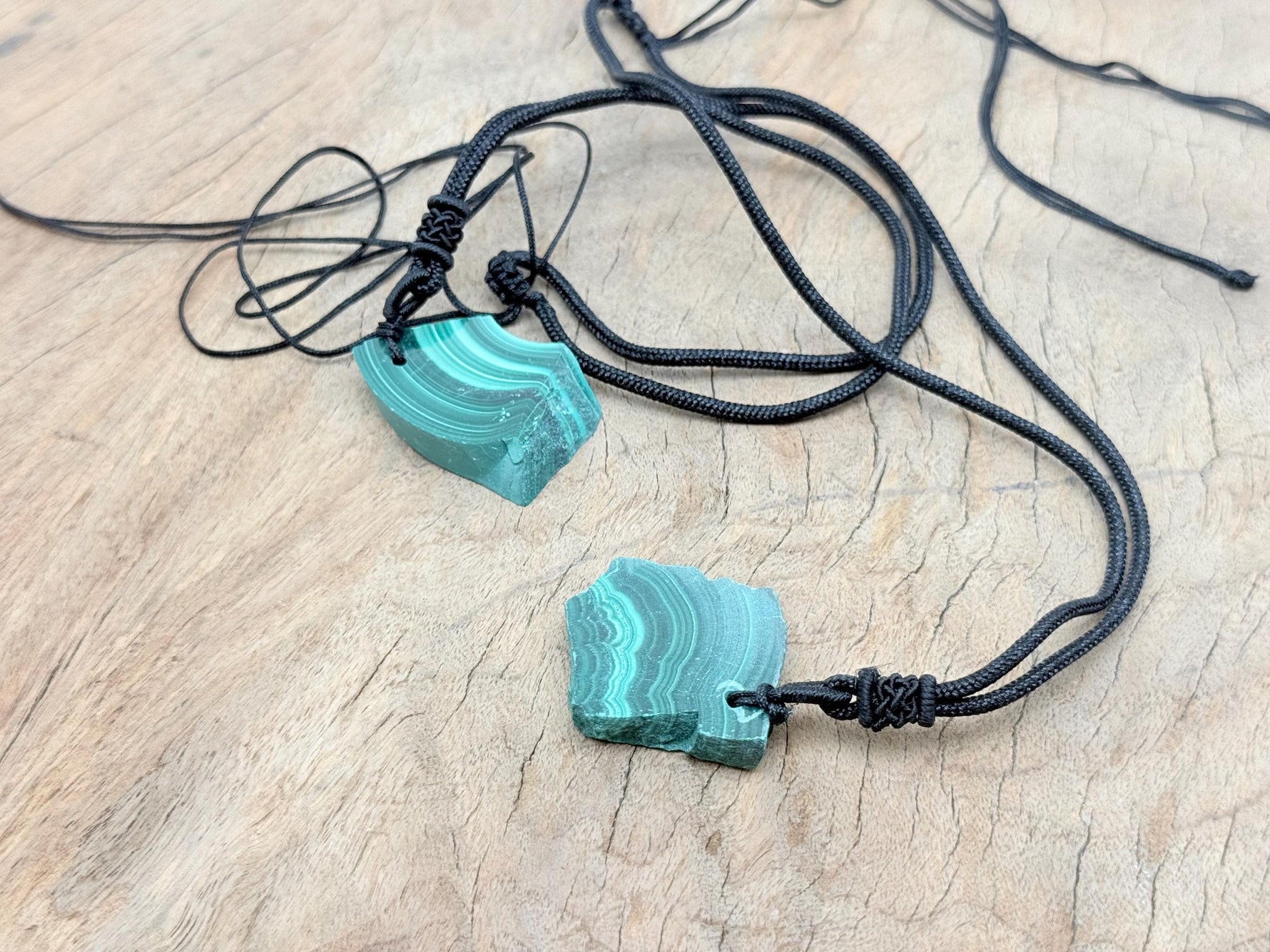Malachite crystal necklace with adjustable cord from GemstoneGO, featuring a polished green stone pendant on a black cord.