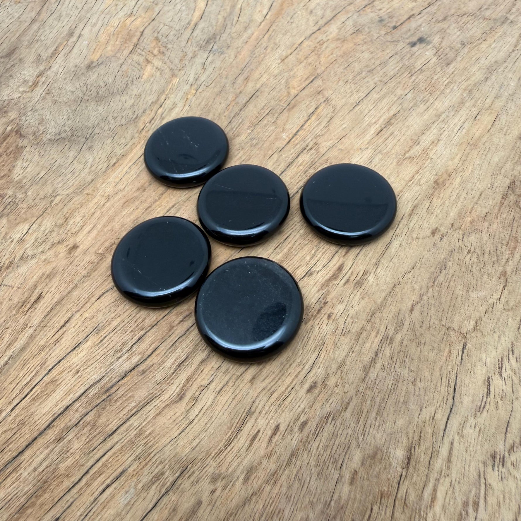 Round obsidian flat gemstone slab, 25mm, from GemstoneGO, showcasing a smooth, polished black crystal surface.