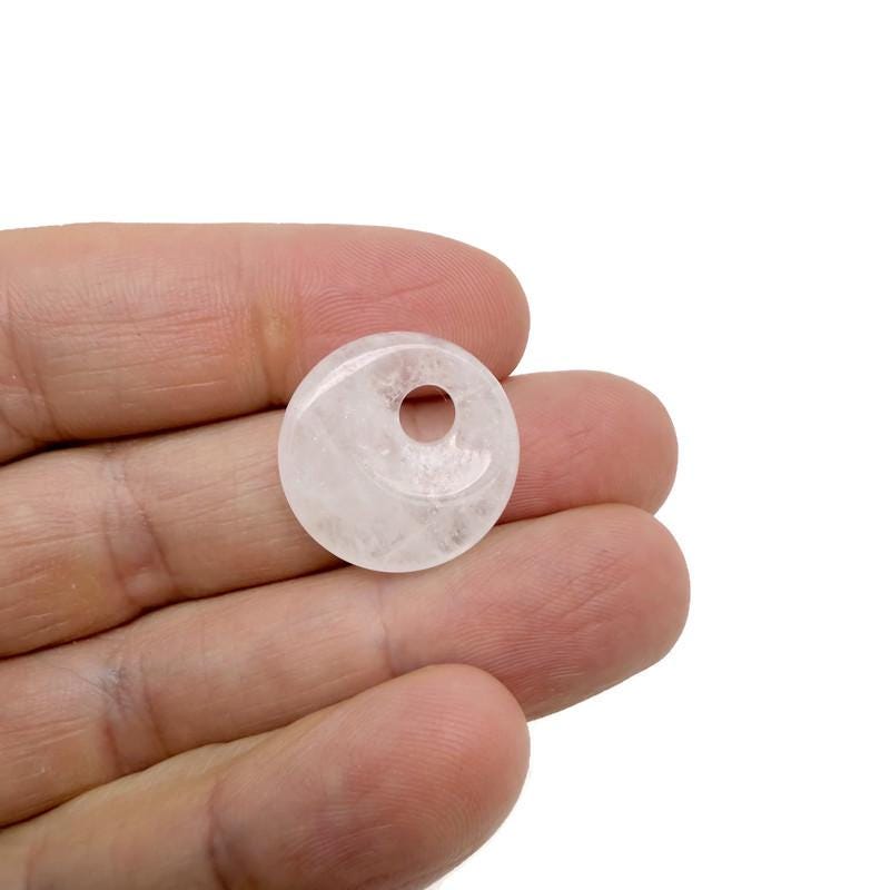 Clear Quartz Crystal donut pendant from GemstoneGO, 20mm Pi stone with polished, smooth surface and transparent, shiny appearance.