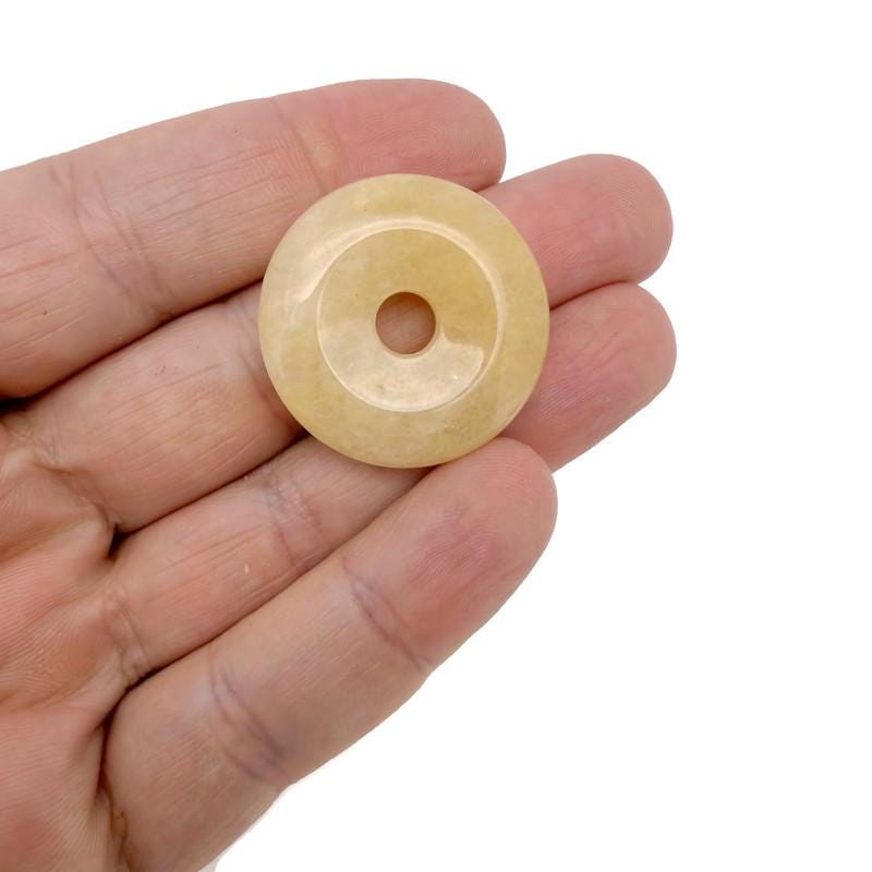 Yellow jade crystal donut pendant from GemstoneGO, 30mm Pi Stone with a polished, vibrant yellow jade gemstone with a smooth, circular shape.