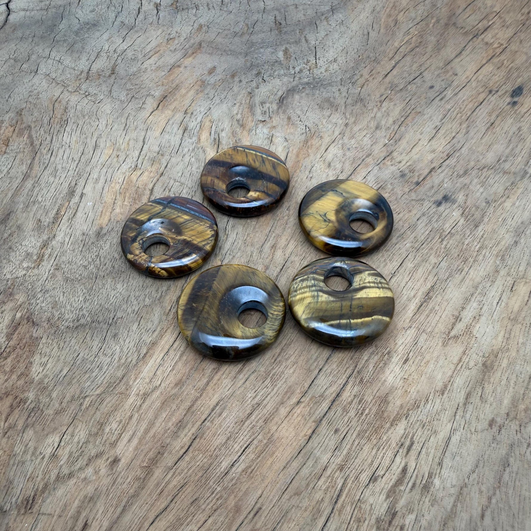 Polished 30mm Tiger Eye crystal donut pendant from GemstoneGO, showcasing golden-brown chatoyancy and smooth, rounded shape.