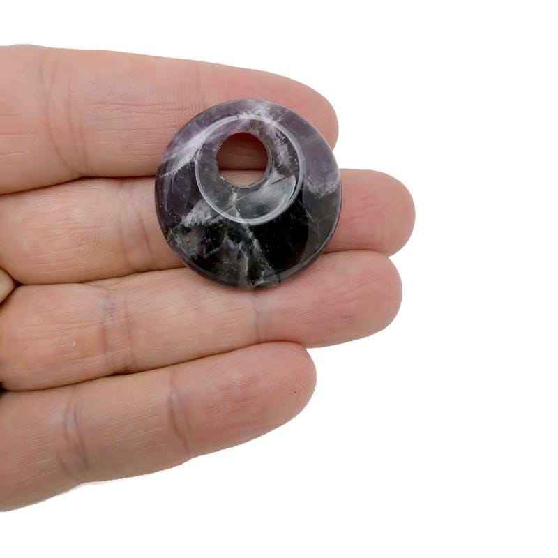 Amethyst crystal donut pendant from GemstoneGO, 30mm Pi stone with purple amethyst hues and polished smooth surface.