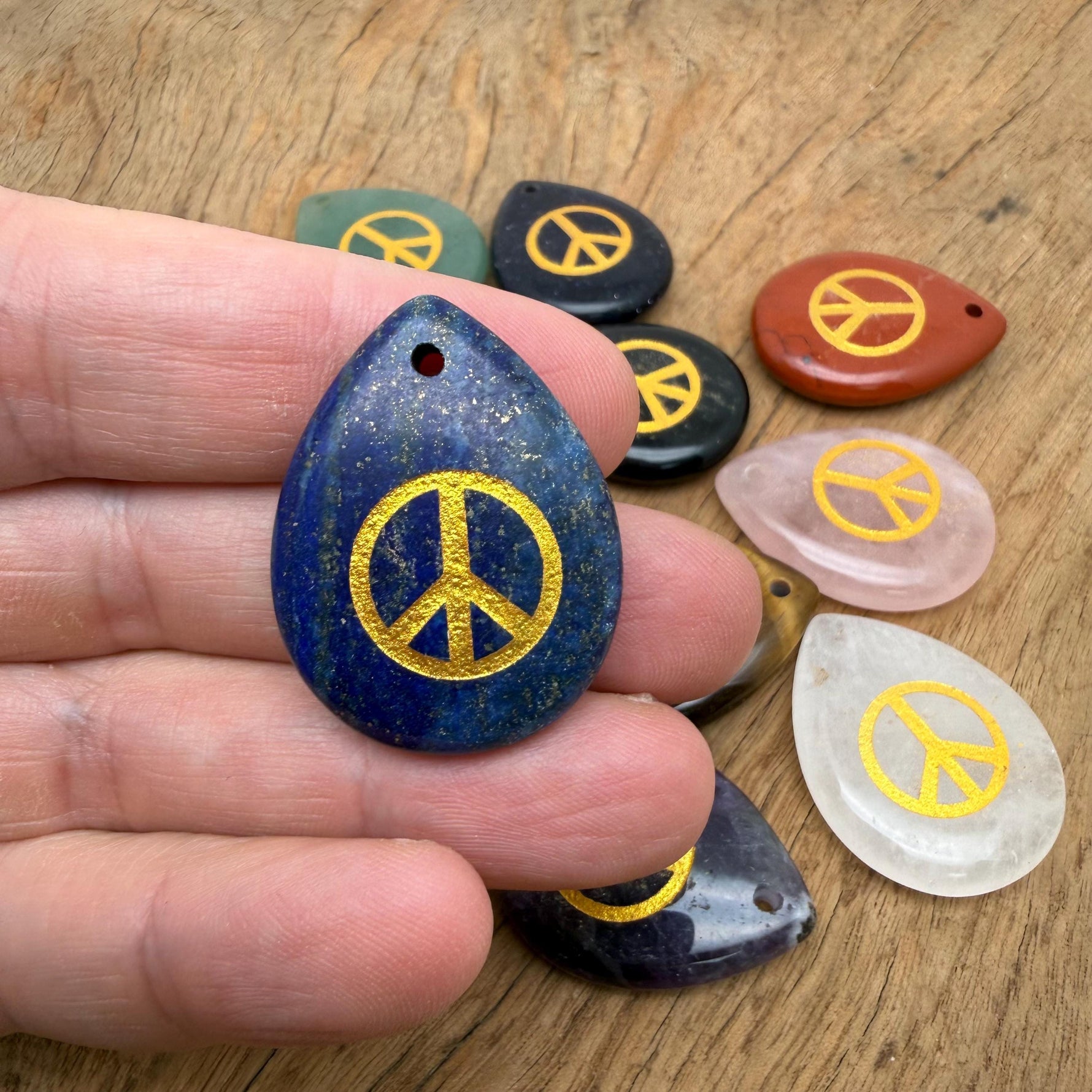 Peace symbol engraved crystal charm with drilled hole, promoting calm, harmony, and positive energy, by GemstoneGO.