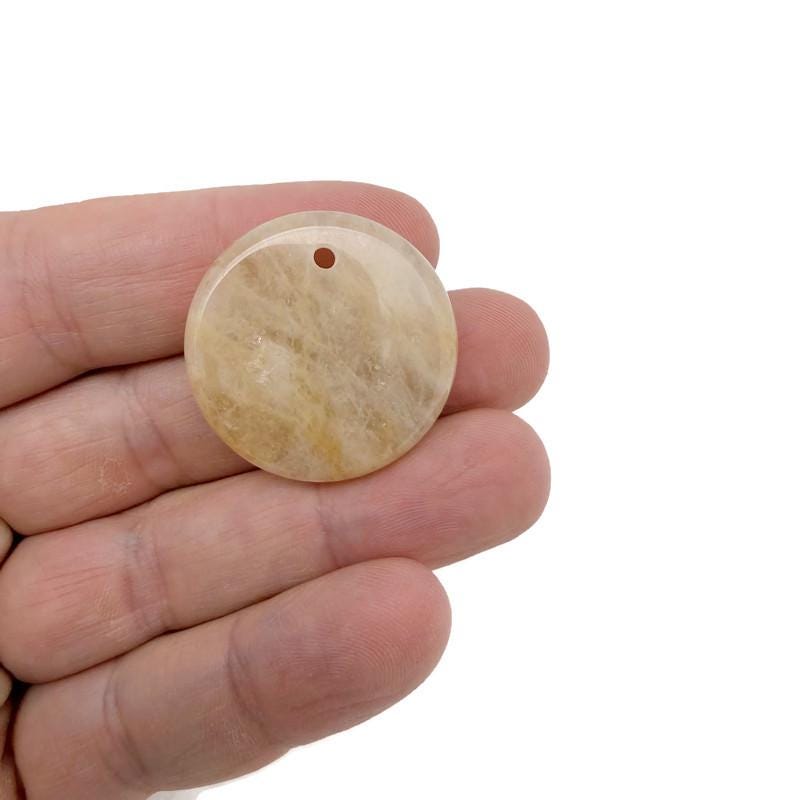 Round gemstone pendant featuring a drilled natural crystal disc charm, showcasing vibrant colors and unique gemstone patterns.