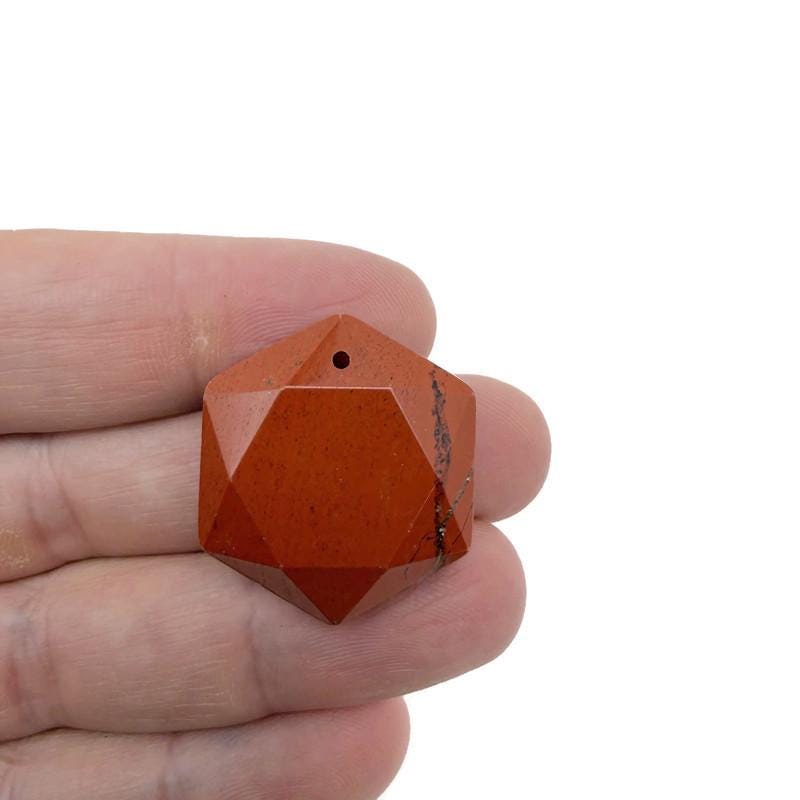 Red Jasper hexagon crystal pendant with faceted stone, hanging on a necklace chain, showcasing its rich red color and geometric shape.