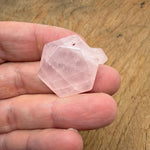 Faceted rose quartz hexagon crystal pendant necklace with gemstone bead, showcasing a pink, polished stone on a delicate chain.