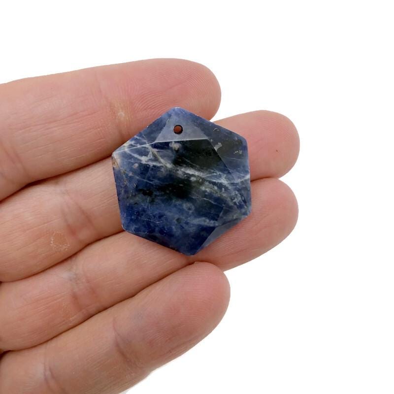 Faceted blue Sodalite hexagon crystal pendant on a necklace, showcasing a polished gemstone bead with natural stone patterns.
