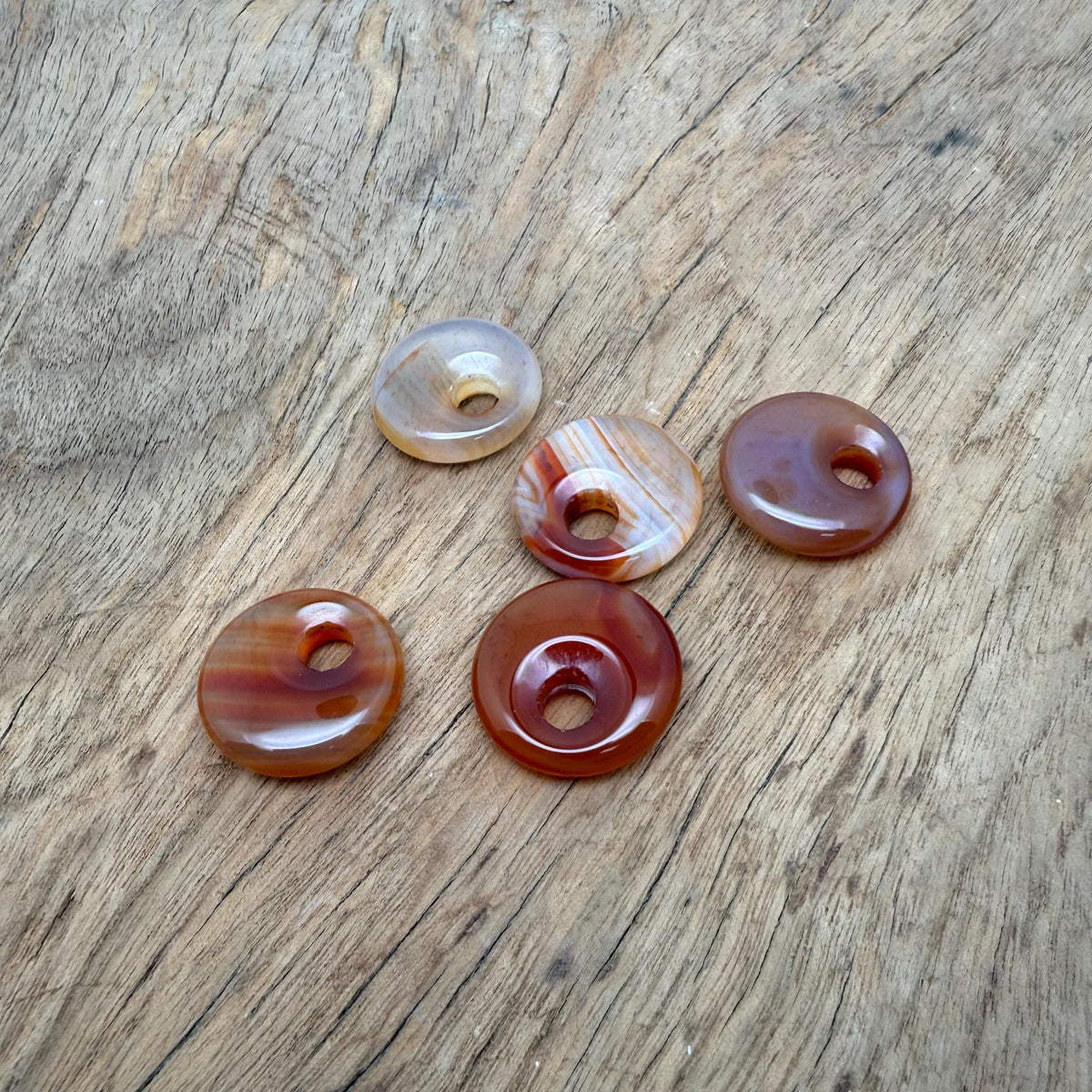 Polished 20mm carnelian crystal donut pendant with vibrant orange color and natural stone texture, from GemstoneGO.