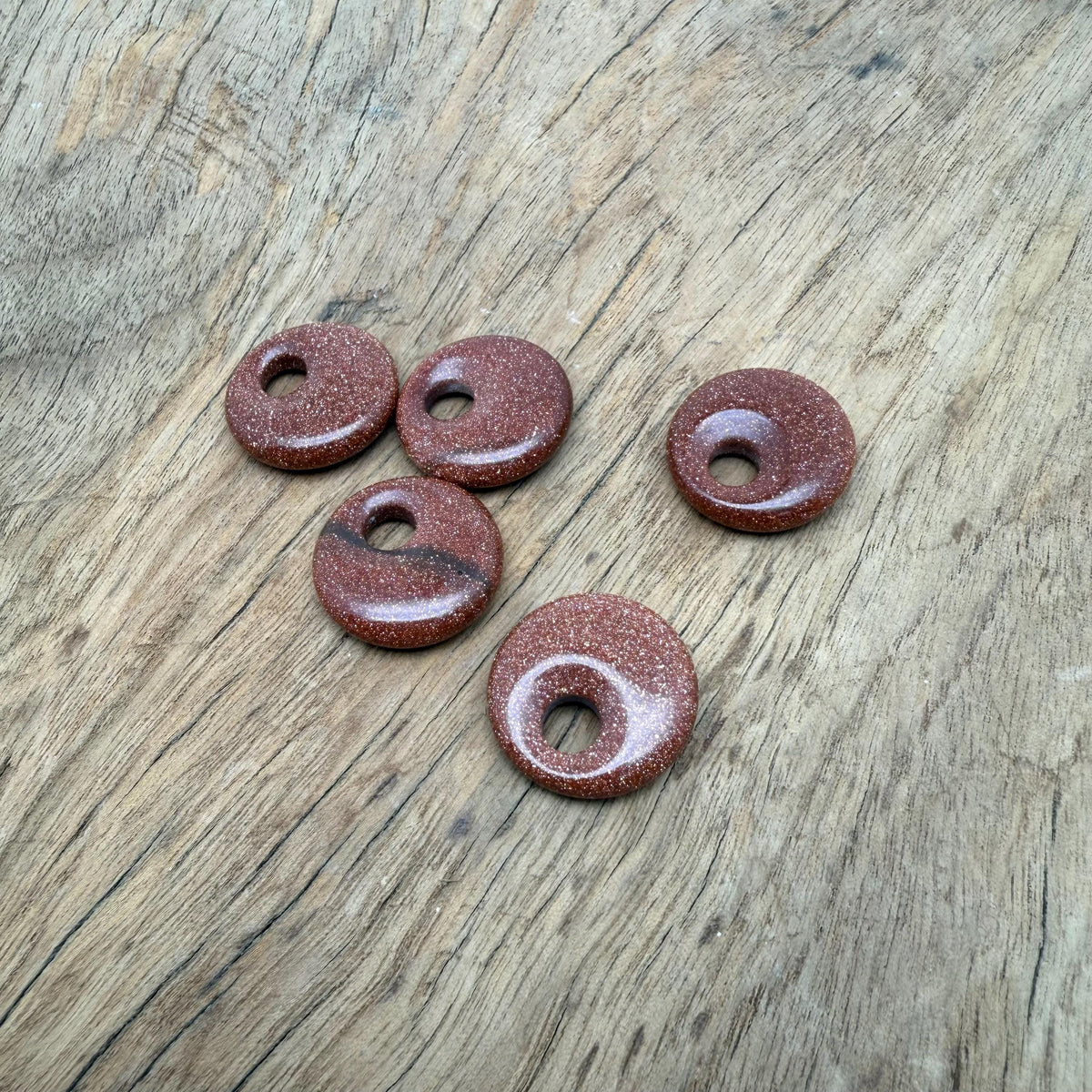 Goldstone crystal donut pendant, 20mm Pi stone from GemstoneGO, showcasing a shimmering gold and brown surface with a hole in the center.