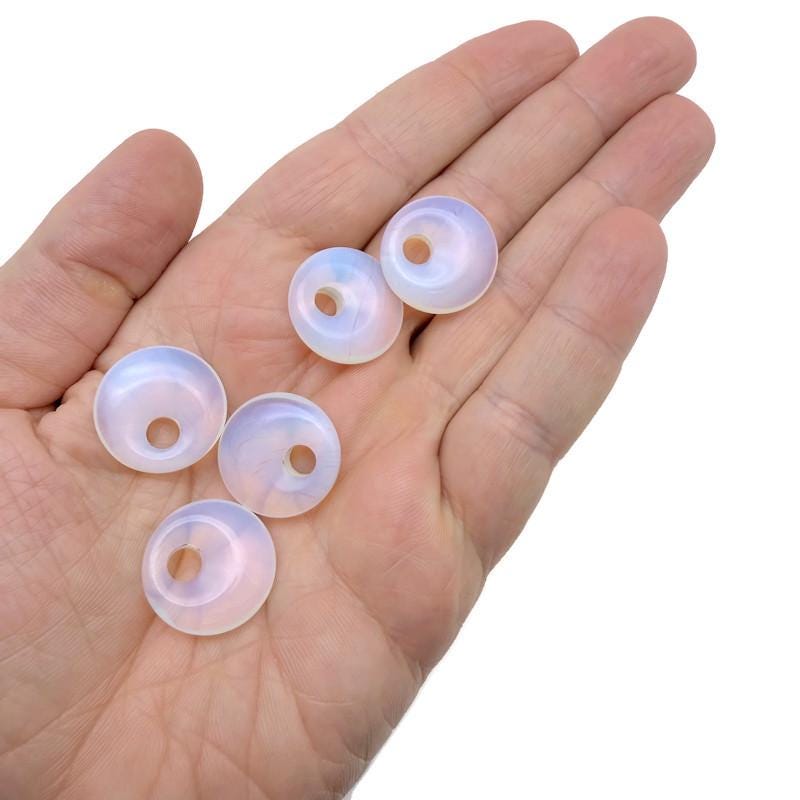 Opalite crystal donut pendant, 20mm Pi stone from GemstoneGO, showcasing a smooth, polished, oval-shaped gemstone with a luminous glow.