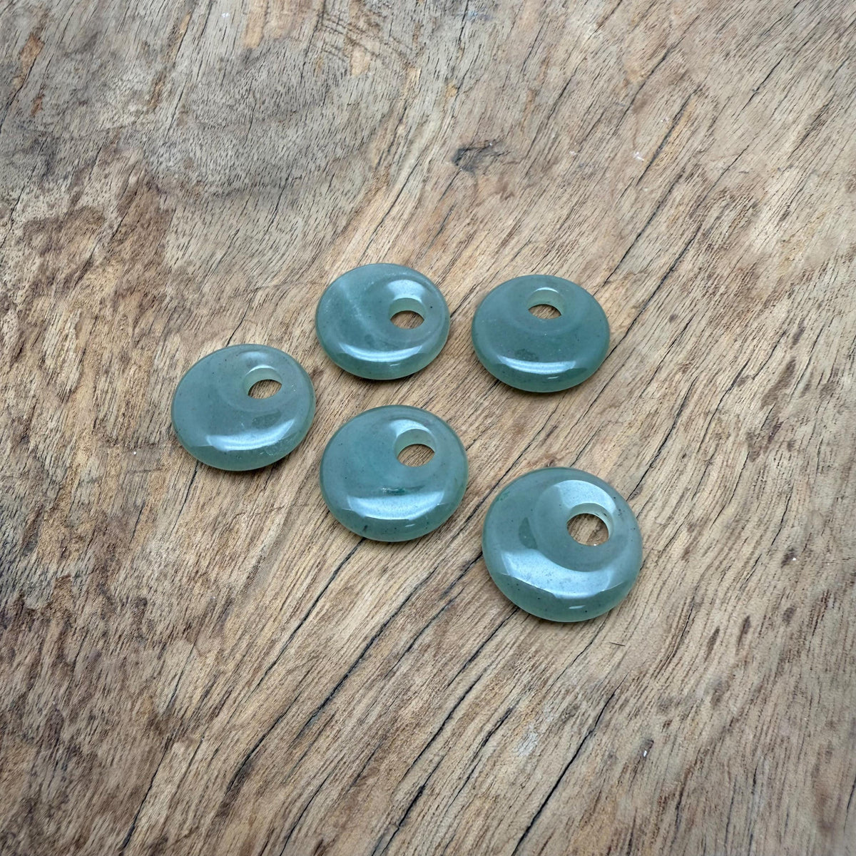 A 20mm aventurine crystal donut pendant with natural green hues and smooth polished surface, showcasing gemstone beauty.