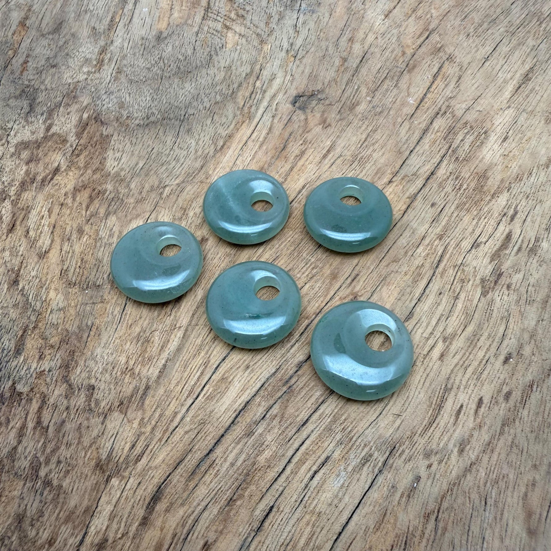 A 20mm aventurine crystal donut pendant with natural green hues and smooth polished surface, showcasing gemstone beauty.