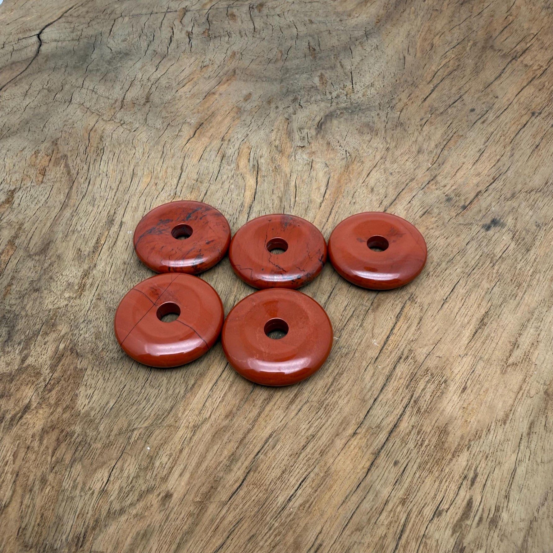 Red Jasper crystal donut from GemstoneGO, 30mm Pi stone with vibrant red and earthy tones, polished and smooth surface.
