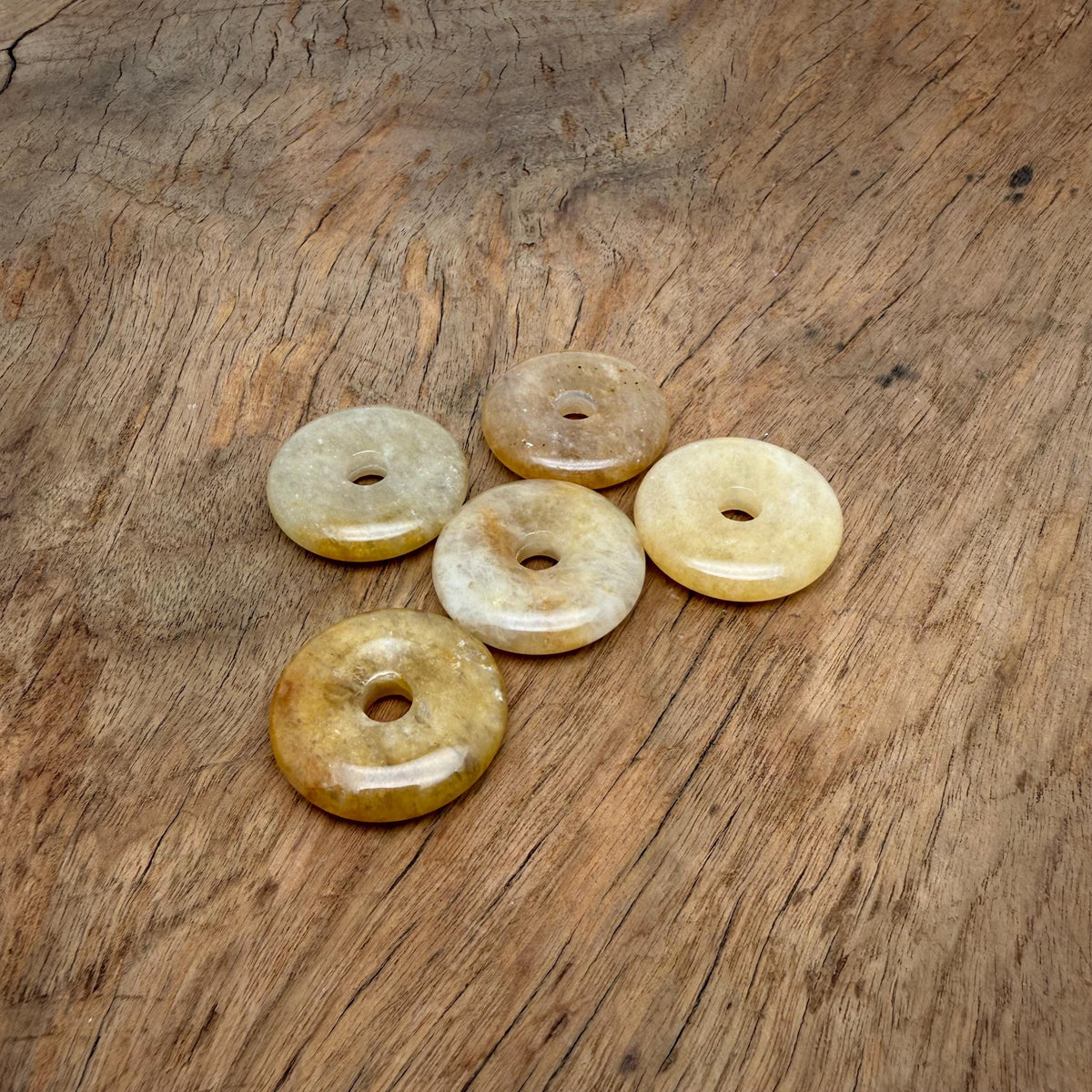 Yellow jade crystal donut pendant, 30mm Pi stone from GemstoneGO, showcasing a smooth, polished yellow jade donut with carved details.