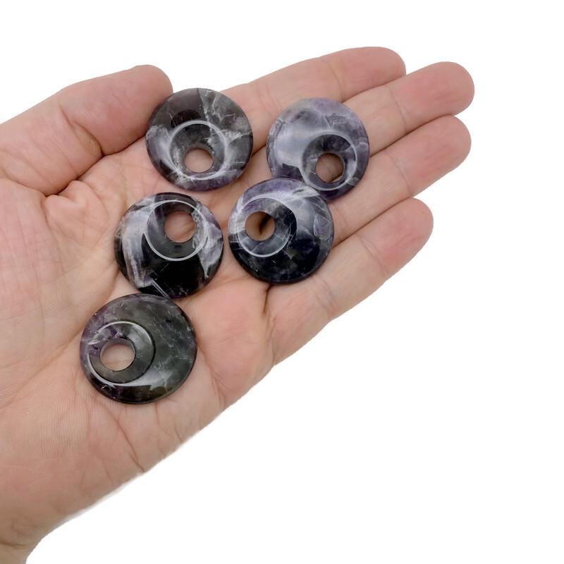 Amethyst crystal donut pendant from GemstoneGO, 30mm Pi stone with purple gemstone and polished finish, showcasing a smooth, rounded shape.