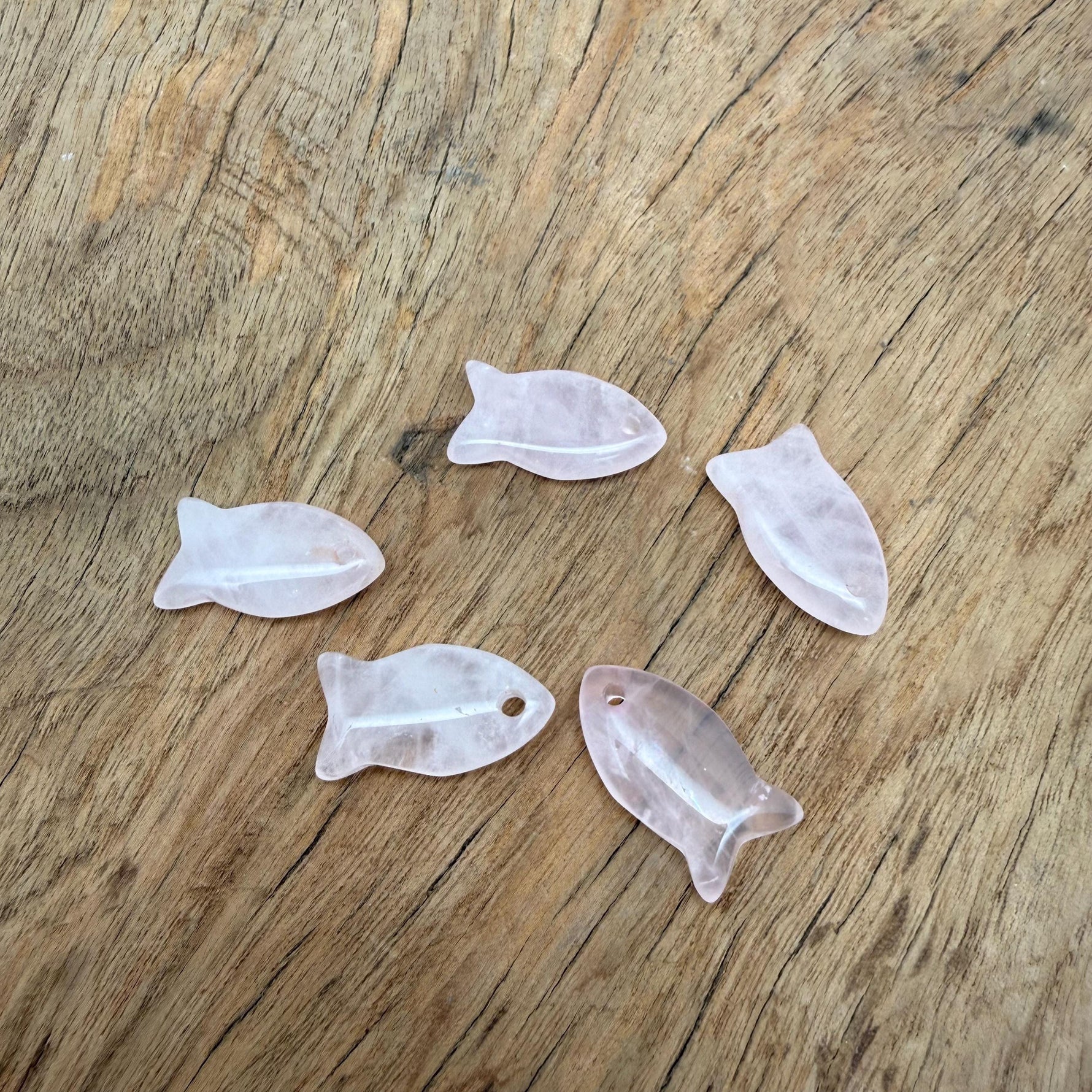 Rose quartz fish-shaped crystal pendant with a silver bail, featuring a smooth, polished healing stone in a fish charm design.