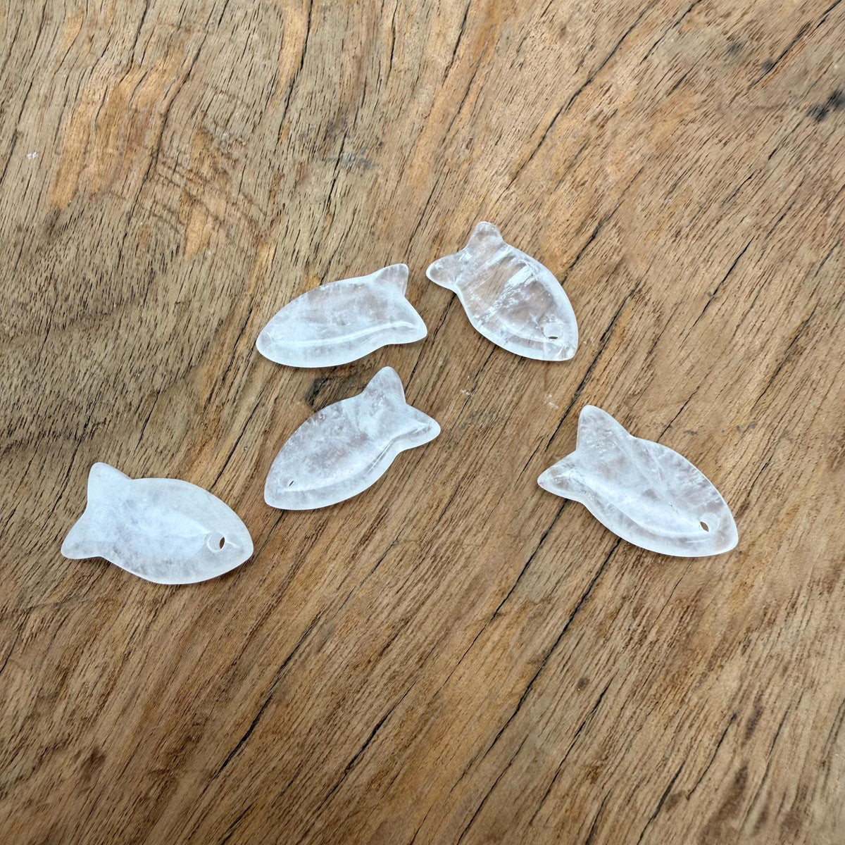 Clear quartz fish-shaped crystal pendant with a silver loop, designed for jewelry and healing stone purposes.