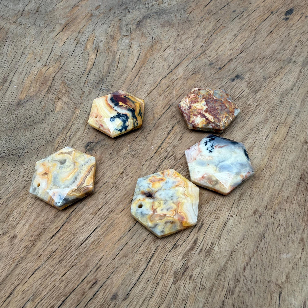 Faceted Crazy Lace Agate hexagon crystal pendant on a necklace, showcasing vibrant banded stone and polished surface.
