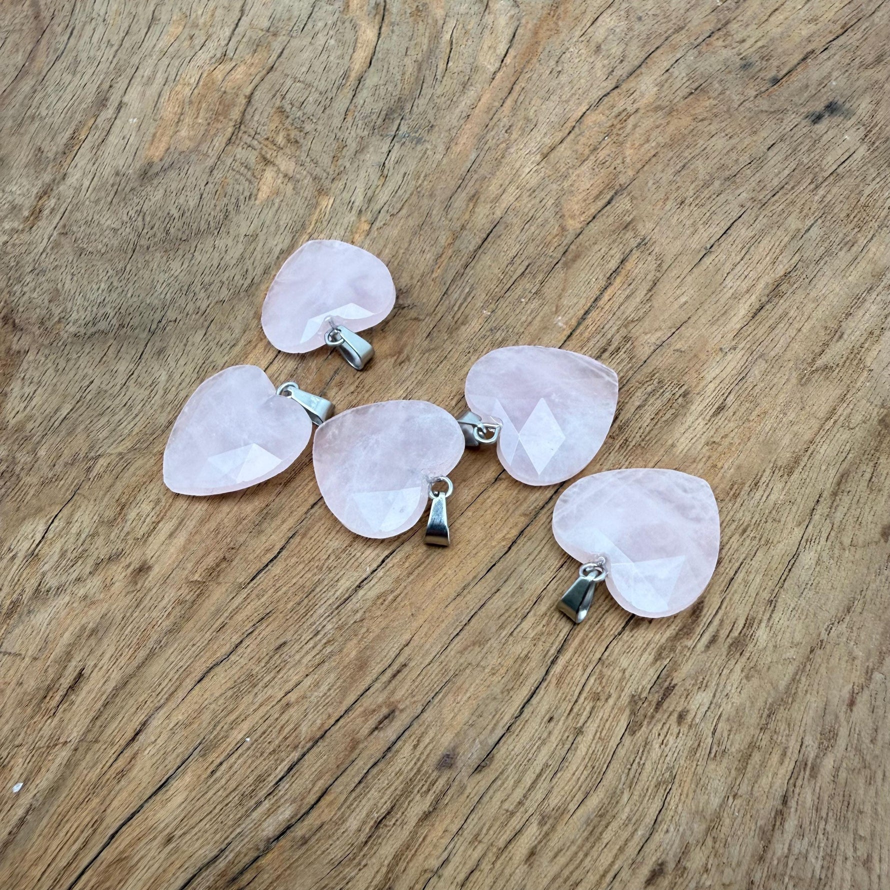 Faceted rose quartz heart crystal pendant with natural gemstone charm, showcasing pink hues and polished facets.